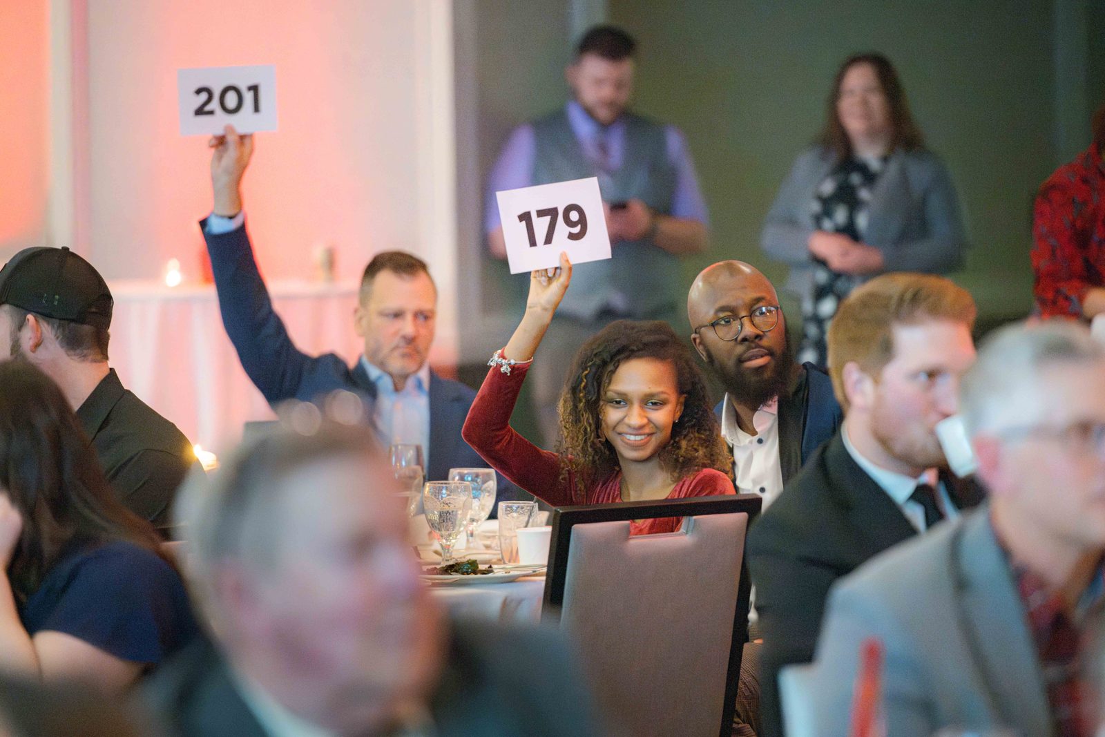 Smiling guests raise bid paddles 201 and 179 during the benefit auction at the Do Good Gala