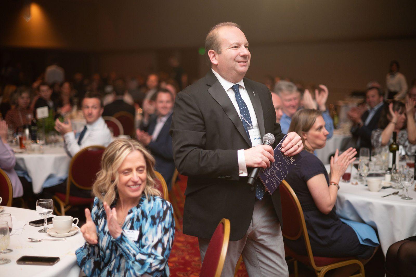Guests applaud as benefit auctioneer Geoffrey Sandler works the room with a microphone at Clean Wisconsin's Epicurean Evening