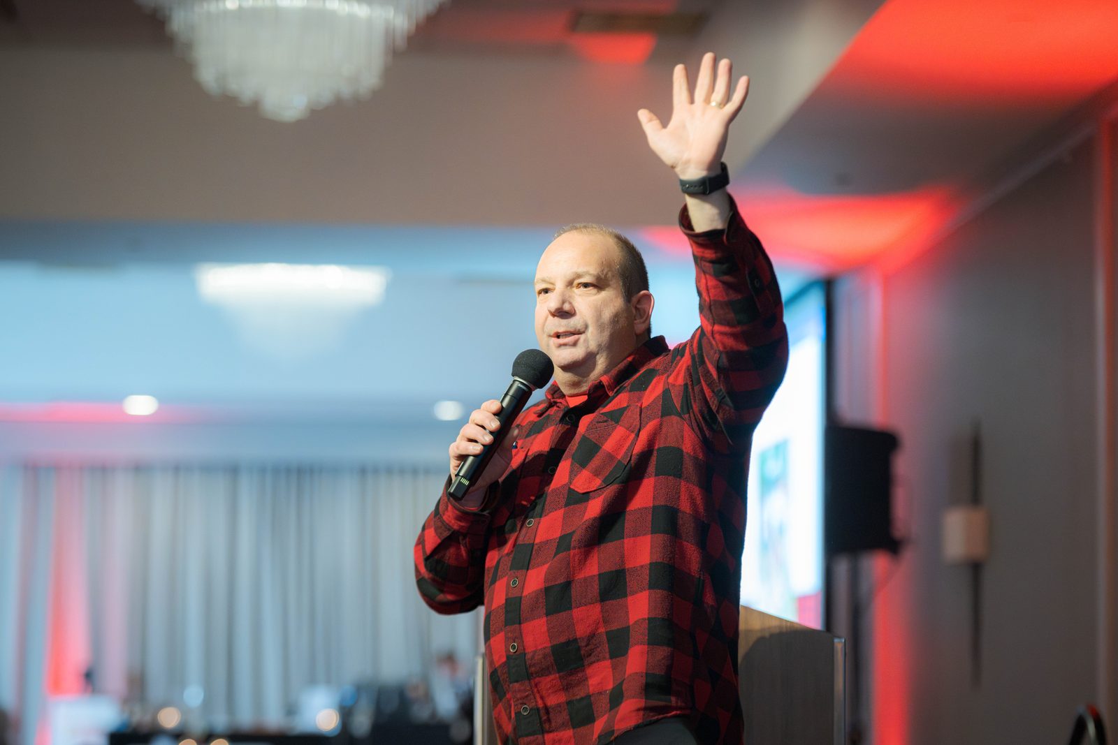Benefit auctioneer Geoffrey Sandler raises his hand to call for bids, microphone in hand, during the live auction at the Do Good Gala
