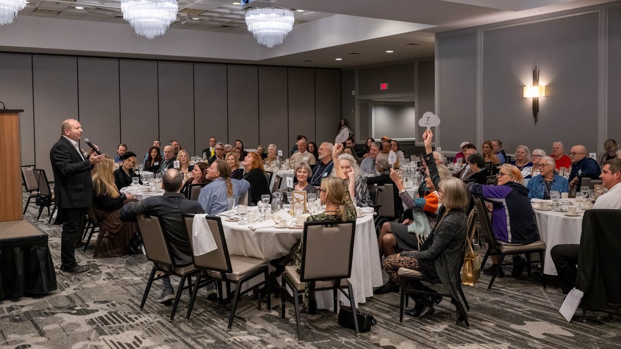 Benefit auctioneer Geoffrey Sandler takes bids on the floor as a guest raises a paddle in a full ballroom at Primates Incorporated's Big Swing fundraiser