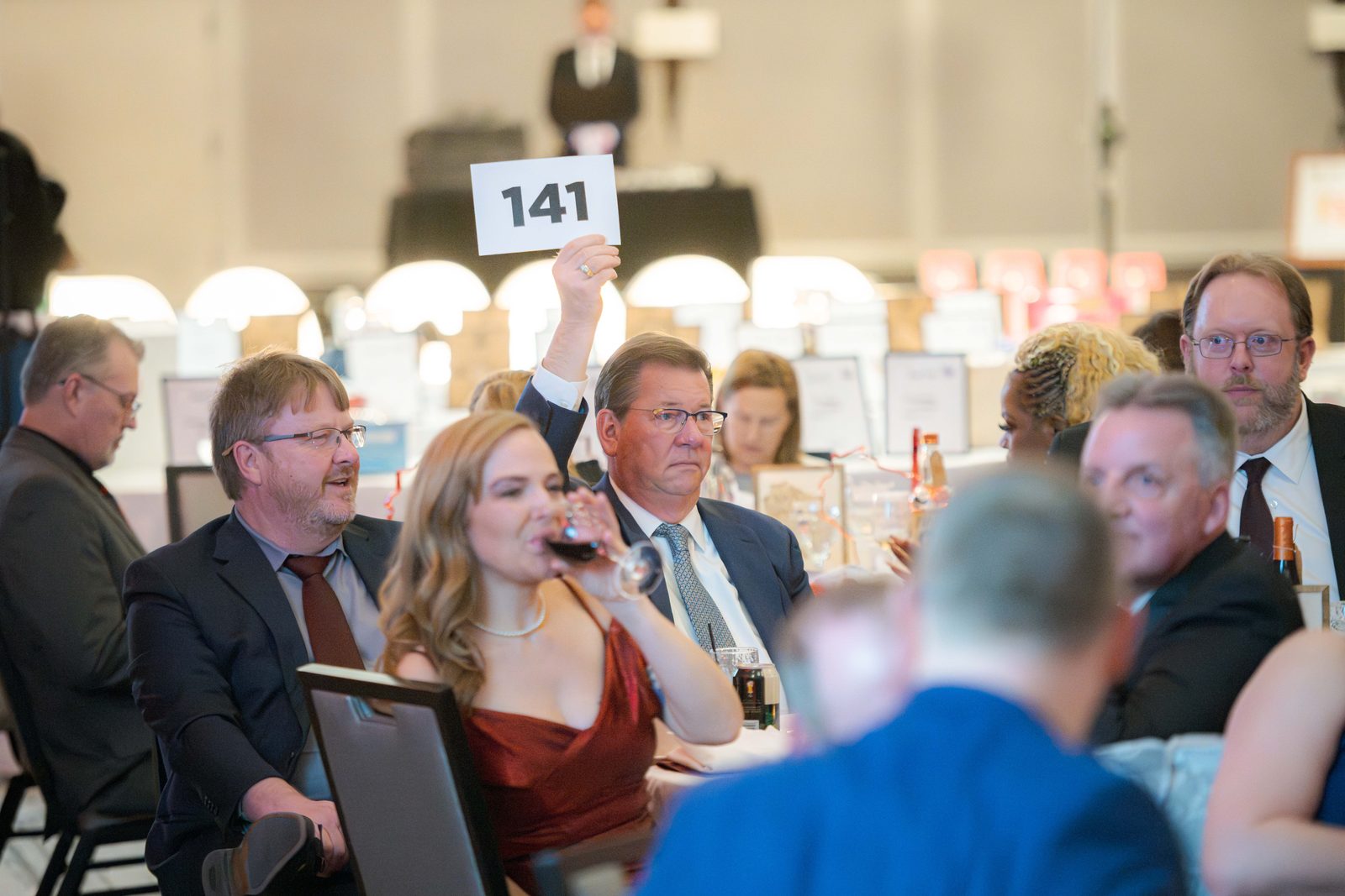 A guest raises bid paddle 141 during the live auction at the Do Good Gala