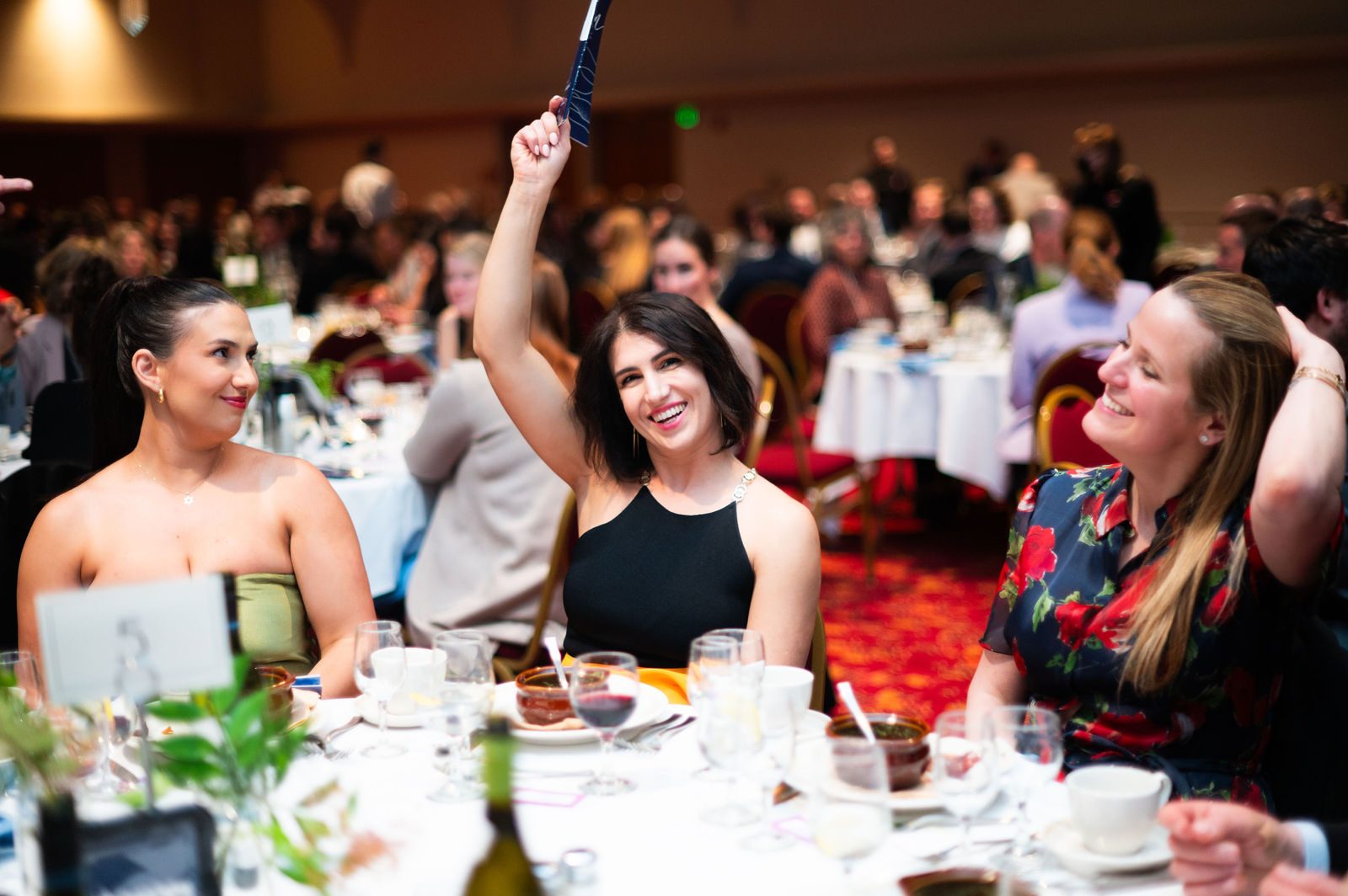 Excited guests raise their bid cards and cheer during the benefit auction at Clean Wisconsin's Epicurean Evening